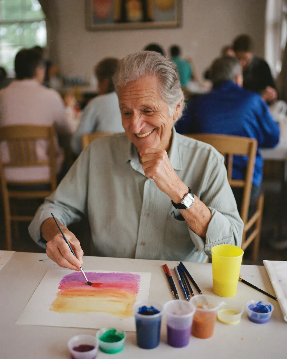 An older man smiling as he paints a watercolor